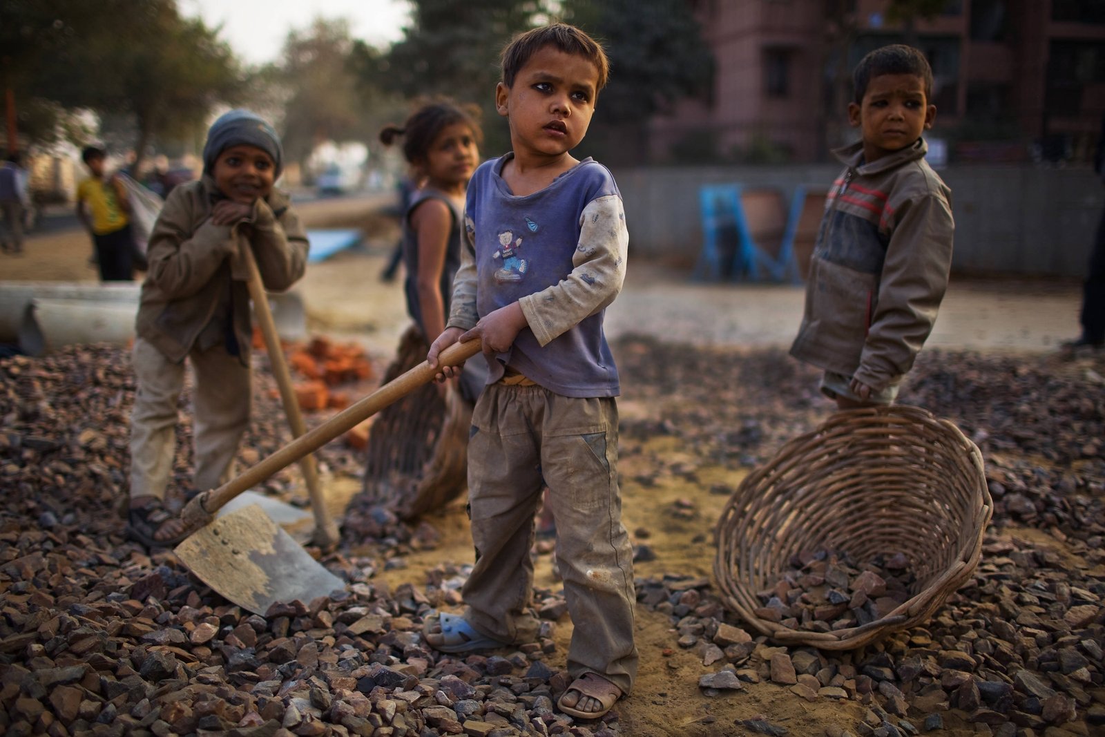DELHI, INDIA  JANUARY 30:  Indian children work nearby to their parents at a construction project in front of the Jawaharlal Nehru Stadium on January 30, 2010 in New Delhi, India. The children accompany their parents to the work site, where if they are prepared to work, they will receive money for bread an milk and be provided with dinner by the contractor.   The Commonwealth Games are due to be held in the Indian capital from October 3-14, 2010, but concerns remain over construction of its sporting and transport infrastructure. The sheer scale of the project has drawn an enormous population of migrant workers from all over India. This week the High Court of Delhi has sought a response from the Government over the alleged failure to provide all the benefits of labour laws to workers involved in construction work for the coming Commonwealth Games. Workers are being paid below the minimum wage in order to complete these projects whilst also being forced to live and work under sub standard conditions. (Photo by Daniel Berehulak/Getty Images)